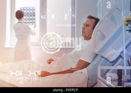 Homme d'âge moyen d'un séjour à l'hôpital et un médecin regardant son X ray Banque D'Images