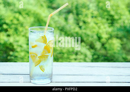 Un verre en sueur avec un cocktail avec de la glace et de citron. Sur un fond de bois. Banque D'Images