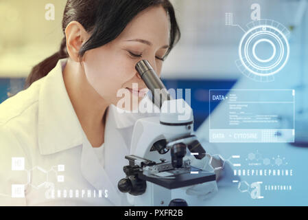 Woman smiling pacifiques tout en travaillant avec un microscope moderne Banque D'Images