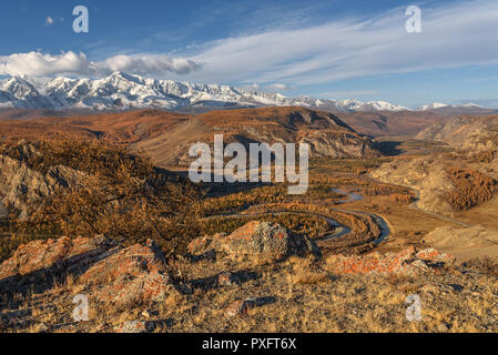 Paysage d'automne avec une étonnante rivière sinueuse, forêt, arbres d'or, route asphaltée et les montagnes couvertes de neige contre un ciel bleu et nuages Banque D'Images