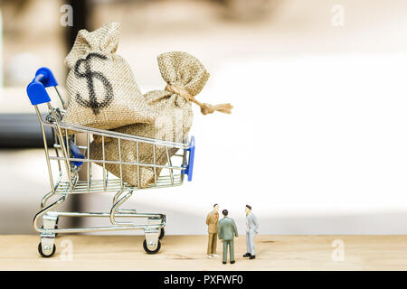 L'investissement financier,négociation discussion entre PDG ou exécuter concept niveau : de l'argent sac dans panier avec trois hommes d'figurine miniature t Banque D'Images
