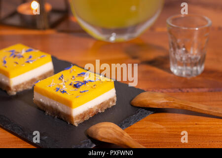 Gâteau à la mangue et citron vert fait maison sur une plaque en pierre noire avec des cuillères en bois Banque D'Images