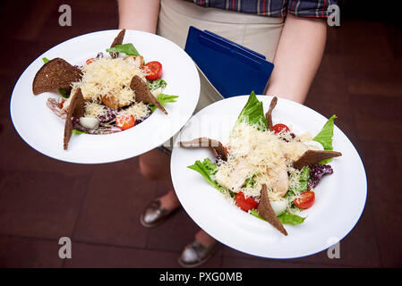 Waiter carrying a plaques avec salade plat. Banque D'Images