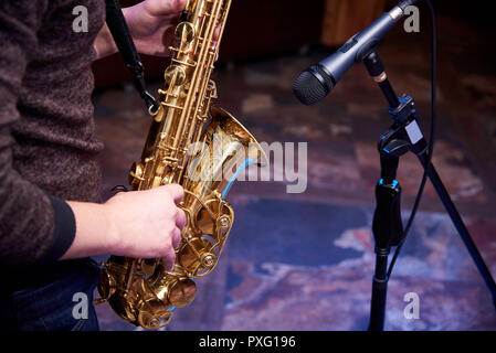 Saxophone d'or dans les mains d'un musicien près du microphone. Banque D'Images