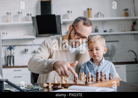 Peu d'enseignement père fils jouant aux échecs à la maison Banque D'Images
