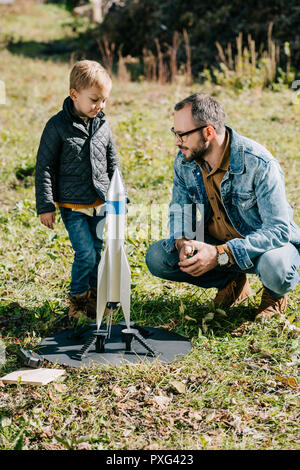 Heureux père et petit fils jouant avec une maquette de fusée Banque D'Images