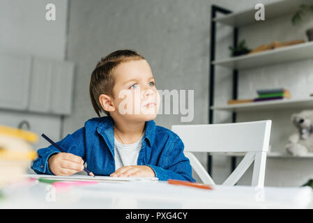 Petit enfant réfléchie dessin avec des crayons de couleurs à la maison Banque D'Images