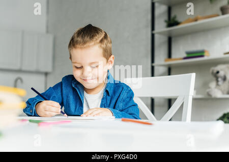 Smiling petit enfant dessin avec des crayons de couleurs à la maison Banque D'Images