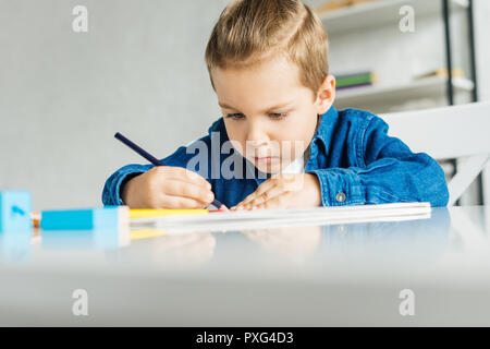 Petit enfant concentré le dessin avec des crayons de couleurs à la maison Banque D'Images