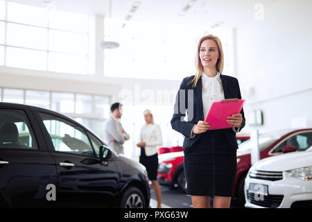 Jeune femme car sales consultant travaillant en salle d'exposition Banque D'Images