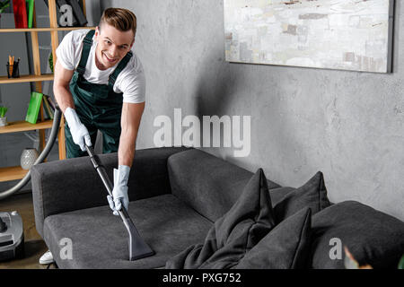 Beau jeune homme dans les gants en caoutchouc et de meubles nettoyage smiling at camera Banque D'Images