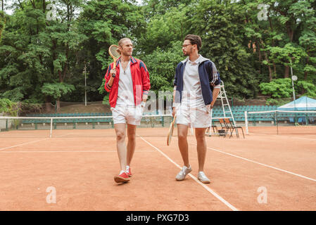 Amis de style rétro avec des raquettes en bois sur pied court de tennis Banque D'Images