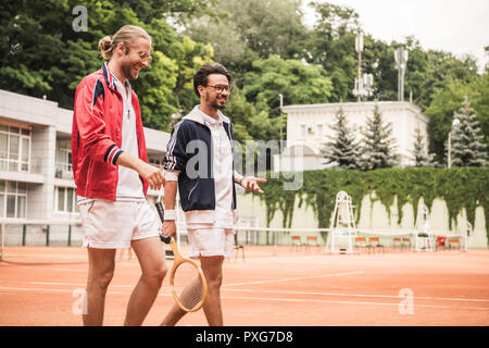 Smiling friends avec raquettes en bois sur pied court de tennis Banque D'Images