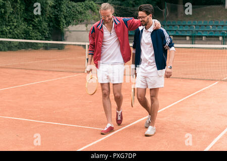 Joyeux amis sportifs avec des accolades et des raquettes de tennis sur marche Banque D'Images