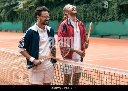 Amis de style rétro de rire avec des raquettes de tennis sur le net avec Banque D'Images