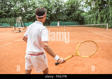 Vue arrière de sportsman jouer au tennis avec raquette de tennis en bois sur Banque D'Images