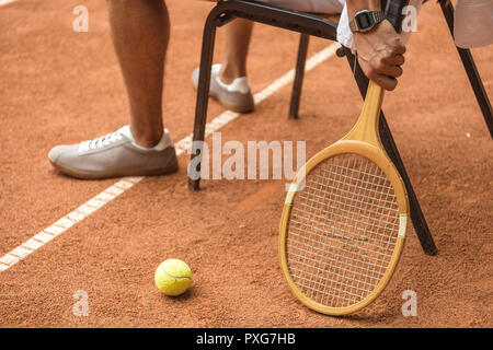 Portrait de joueur de tennis se reposant sur un fauteuil avec raquette en bois rétro et la balle de tennis sur Banque D'Images