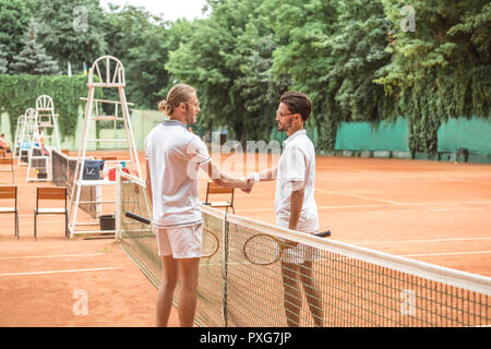 Joueurs de tennis avec des raquettes en bois se serrer la main après match sur cour Banque D'Images
