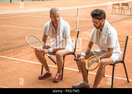 Vieux-fashionedtennis les joueurs avec des raquettes en bois rétro sur des chaises de repos Banque D'Images