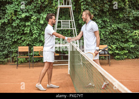 Les joueurs de tennis avec des raquettes en bois se serrer la main après le match sur cour Banque D'Images