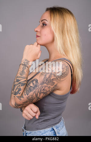 Belle jeune femme aux cheveux blonds contre l'arrière-plan gris Banque D'Images