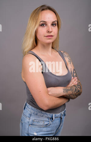 Belle jeune femme aux cheveux blonds contre l'arrière-plan gris Banque D'Images