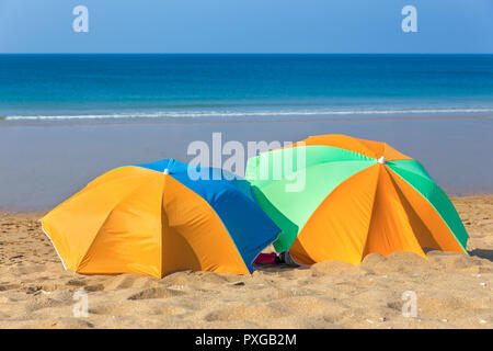 Deux parasols colorés sur la plage par la mer Banque D'Images