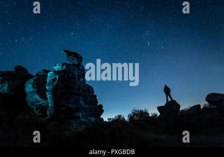 NOTE DU RÉDACTEUR : PHOTO PRISE AVEC UNE VITESSE D'OBTURATION LENTE un avion passe par comme un homme stargazes à Brimham Rocks dans le Yorkshire, comme la pluie de météore Orionid atteint son maximum. Banque D'Images