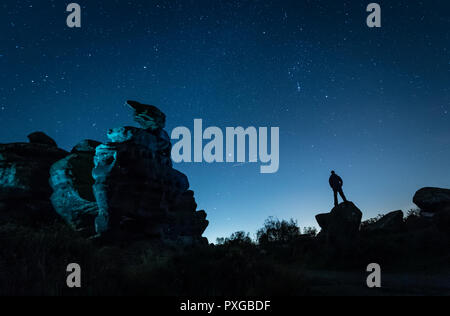 NOTE DU RÉDACTEUR : PHOTO PRISE AVEC UNE VITESSE D'OBTURATION LENTE un avion passe par comme un homme stargazes à Brimham Rocks dans le Yorkshire, comme la pluie de météore Orionid atteint son maximum. Banque D'Images