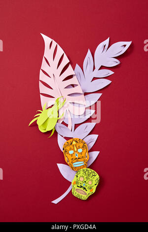 Un papier coloré composition de diverses feuilles colorées et comté de la maison de vacances mexicaines de Calaca sur fond rouge avec l'espace pour le texte. Artisanat Halloween carte postale. Mise à plat Banque D'Images