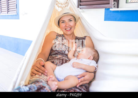 Mère et son petit baby boy relaxing in hammock en face de la maison Banque D'Images