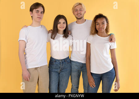 Groupe multiracial d'amis en blanc T-shirts sur fond jaune. Banque D'Images