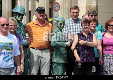 Un groupe d'heureux touristes sont sur une visite guidée de Berlin, mais, ils semblent ignorer qu'ils semblent avoir été rejoint par deux vert, les artistes de rue le long du chemin. Banque D'Images