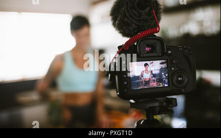 Jeune femme de l'enregistrement vidéo sur appareil photo en cuisine. Shot appareil photo de fruits coupe femme montrant en cuisine. Banque D'Images