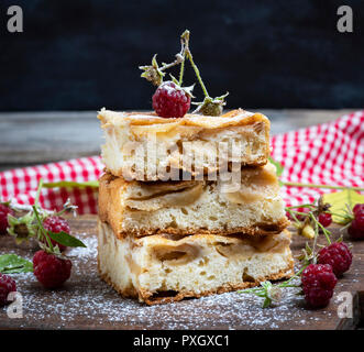 Petits morceaux carrés de tarte aux pommes sont empilés sur une planche de bois brun, éponge pie Banque D'Images