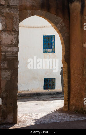 Rue avec une chambre avec fenêtre bleu vif et grilles de couleur blanche de la façade. Passage souterrain en pierre au premier plan. La Kasbah de Oudaias, Rabat, Maroc. Banque D'Images