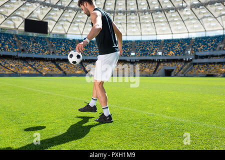 Jeune et beau joueur de foot balle rebondissante sur jambe à stade Banque D'Images