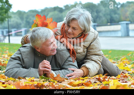 Portrait of happy senior couple lying in park Banque D'Images