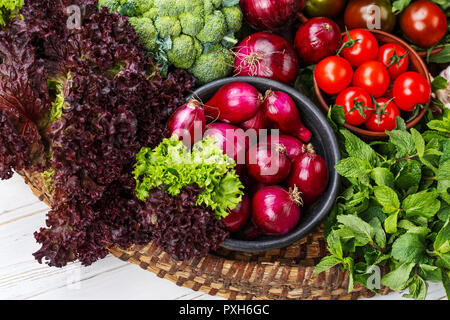 Sur un fond de bois blanc, un panier de légumes frais. Banque D'Images