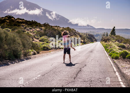 Jeune homme et femme en rapport ensemble marcher au milieu d'un long chemin à la montagne. Pieds nus homme, une belle jeune fille sur sa poitrine et wal Banque D'Images