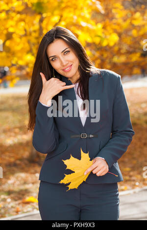 Happy Businesswoman with hand show avec call ma sign, autumn park background Banque D'Images