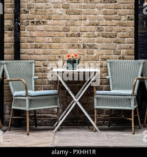 Une table et deux chaises avec une théière pleine de fleurs à l'extérieur d'un café sur Clink Street, London, England Banque D'Images