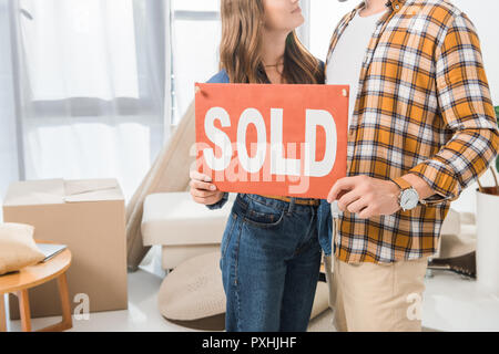 Vue partielle de couple holding vendu carte rouge à la maison avec des boîtes en carton Banque D'Images