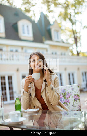 Portrait of young woman sitting in beau élégant café de la ville, à l'aide de téléphone mobile et boit du café Banque D'Images