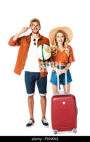 Smiling couple standing avec loupe, Globe and travel bag isolated on white Banque D'Images