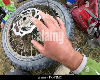 Blessures de la main sur la moto et réparation roue dans les montagnes Banque D'Images