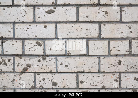 Mur de brique de boue blanc taché d'éclaboussures. Banque D'Images