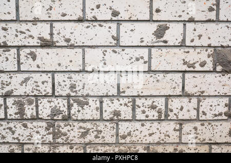 Mur de brique de boue blanc taché d'éclaboussures. Banque D'Images