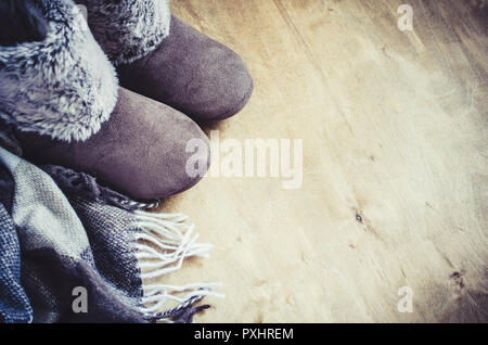 Accueil vêtements chauds. Plaid en laine et des chaussons sur fond de bois. Banque D'Images