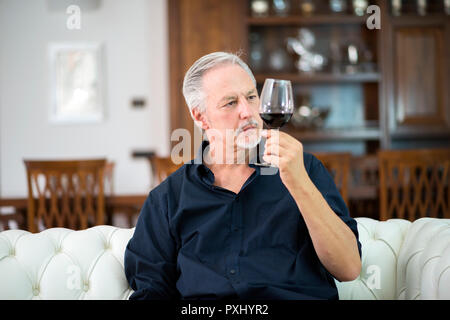 Portrait d'un homme mûr bénéficiant d''un verre de vin rouge à la maison Banque D'Images